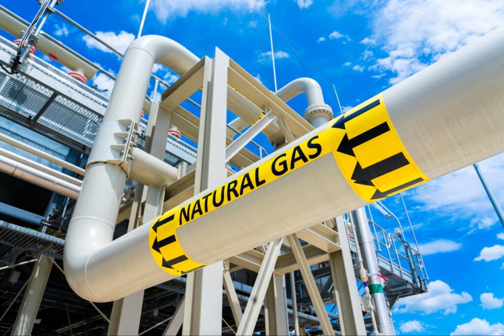 Natural gas pipeline with high pressure and direction sign at compressor station.